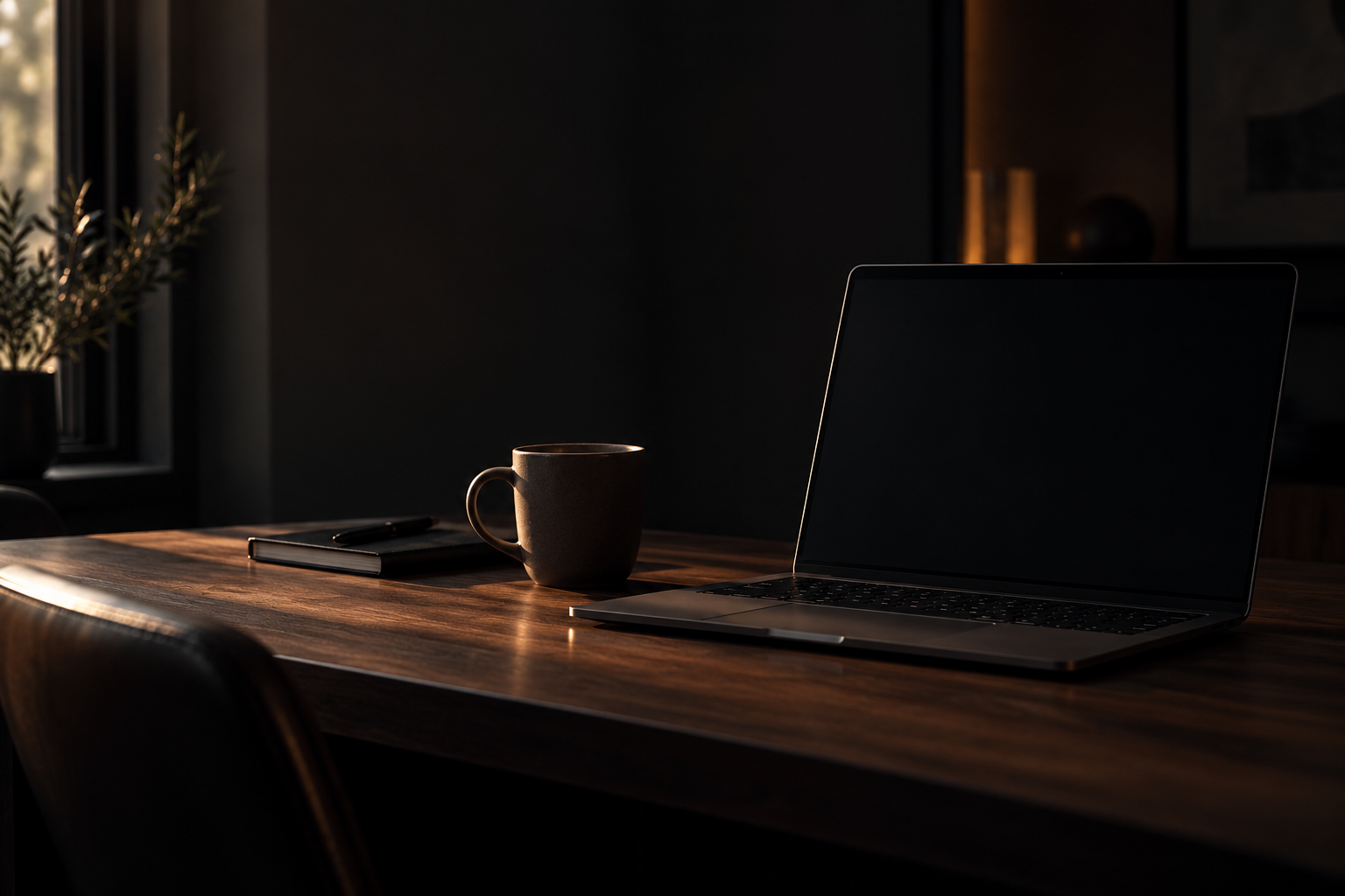 A laptop on a dark wooden desk showing a CRM screen, lit from the side